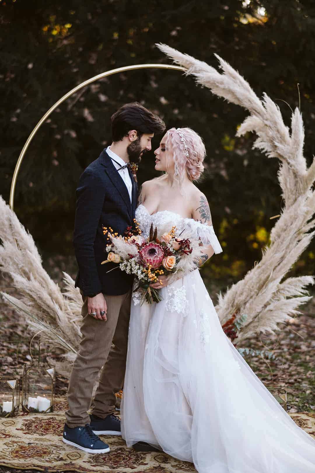 https://www.bespoke-bride.com/wp-content/uploads/2021/09/Autumnal-themed-wedding-with-pampas-grass-floral-arrangements-Tattooed-bride-with-pink-hair-wearing-an-off-the-shoulder-lace-wedding-dress-18.jpg